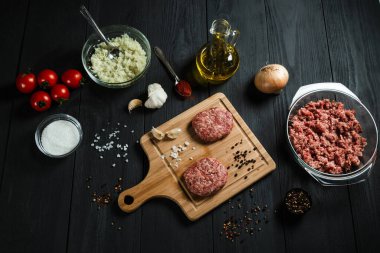 Siyah ahşap masadaki malzemelerle doğranmış etten pirzola. Ev yemeği..