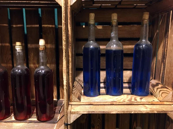 Old Bottles of Wine in a Wooden Wine Box. Vintage wooden wine crate. Bottles of colored drinks in gift wooden box. Bottles in a wooden box. Home winemaking. Wine cabinet made of drawers