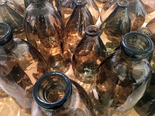 Decorative bottle made of recycled glass, with a rounded raw shape. Large glass vases. Deep Amber Dark Brown Glass Vases. Top view.  Assortment of empty brown glass bottles.