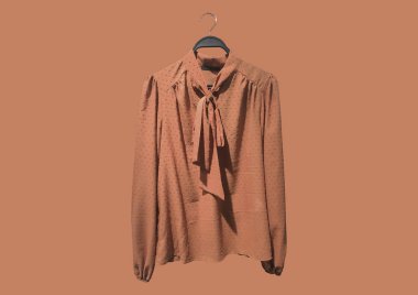 Yakası fırfırlı turuncu kadın bluzu ve turuncu arka planda izole bir askıda kolları var. Asgari düzeyde. Kıyafet kompozisyonu. Moda konsepti modeli. Düz yatıyordu