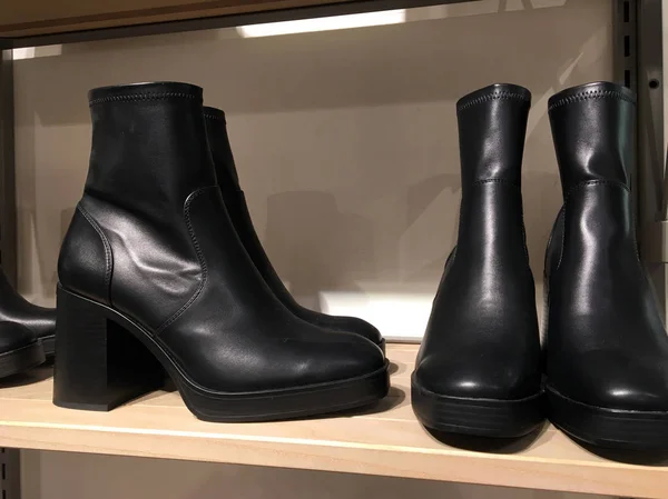 Black boots with contrast stretch legson the shelf. Demonstration of fashionable women's shoes. Mass market shop. Sale of modern women's shoes. Ladies High Heel Boots