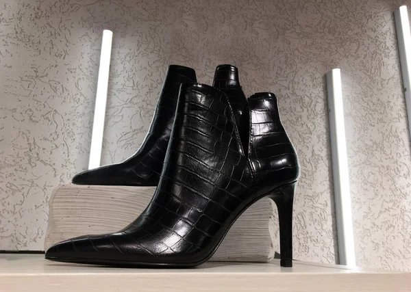 黑色的蟒蛇皮镶嵌脚踝靴 架子上有剪断的细高跟鞋 展示时髦的女鞋 大众市场商店 现代女鞋的销售 女子高跟鞋靴 — 图库照片