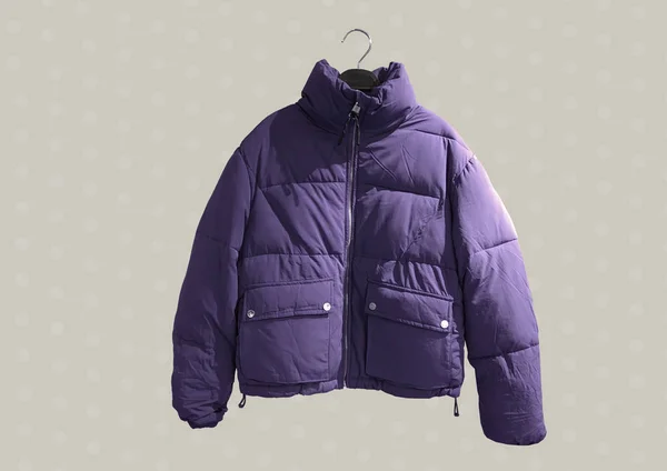 Purple women fashion down jacket pattern. Padded coat with zip fastener isolated on brown background. Winter clothes pattern. Composition of clothes. Flat lay, top view, copy space