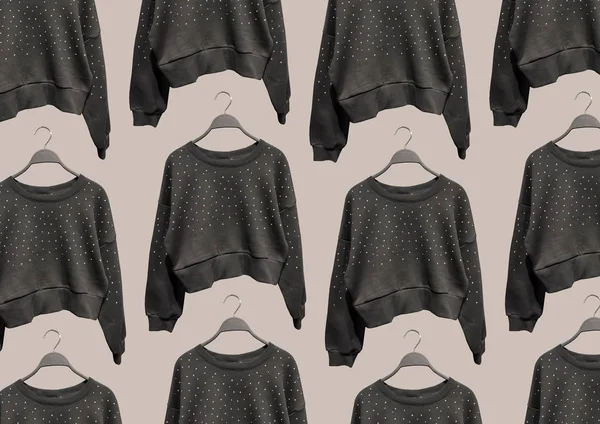 Black round neck sweatshirts with long sleeves and metallic stud appliques on hangers isolated on brown background. Composition of clothes. Flat lay. Minimal style. Composition of clothes. Pattern