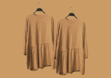 Sarı arka planda izole edilmiş bir askıda uzun kollu sarı, pelüş elbiseler. Kıyafet kompozisyonu. Düz konum, üst görünüm, kopyalama alanı. Giysi deseni. 