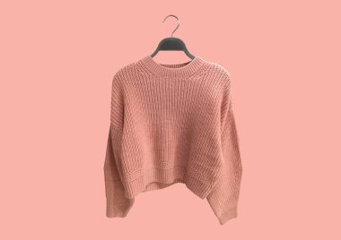 Bej arka planda izole edilmiş askıda pembe büyük boy örgü süveter. Kıyafet kompozisyonu. Banner konsepti. Moda kıyafet kolajı. Moda konsepti. Desen