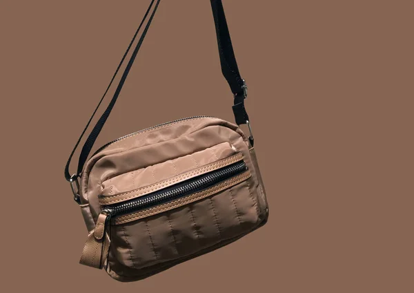 Kahverengi kemer çantası, kahverengi arka planda izole edilmiş. Siyah kuşaklı bel çantası. Moda aksesuarları konsepti. Çapraz ceset torbası. Kıyafet kompozisyonu. Moda kıyafet kolajı