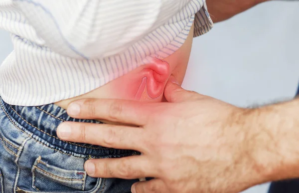 El médico examina al niño, observa el ombligo y la hernia, comprueba el estómago sobre un fondo azul aislado.El concepto de salud de los niños —  Fotos de Stock