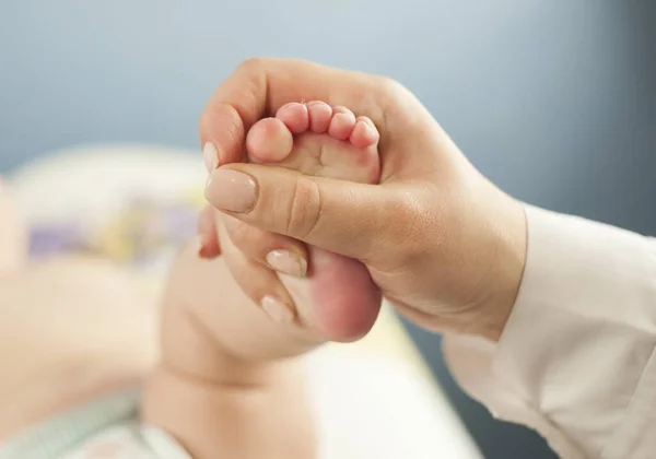 Madre amor Madre sosteniendo los pies de su pequeño bebé, de cerca. Examen de la piel del concepto por un médico —  Fotos de Stock