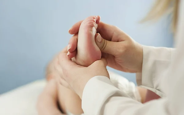 Anne küçük bebeğinin ayaklarını tutarak, yakından anneyi sever. Bir doktor tarafından yapılan cilt muayenesi hariç. — Stok fotoğraf