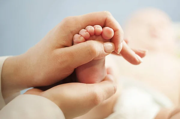 Moeder liefde Moeder houdt haar kleine baby 's voeten, close-up.Concept huidonderzoek door een arts Stockafbeelding