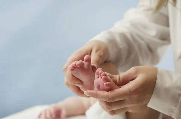 Moeder liefde Moeder houdt haar kleine baby 's voeten, close-up.Concept huidonderzoek door een arts Stockfoto