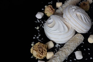 Metin için açık alanı olan siyah bir arkaplan üzerindeki hava beyaz marşmelovlarının görüntüsü.