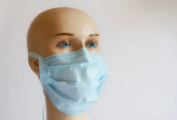 Image of a blue mask on the face of a gypsum mannequin. covid-19 virus concept, on bright backgroun