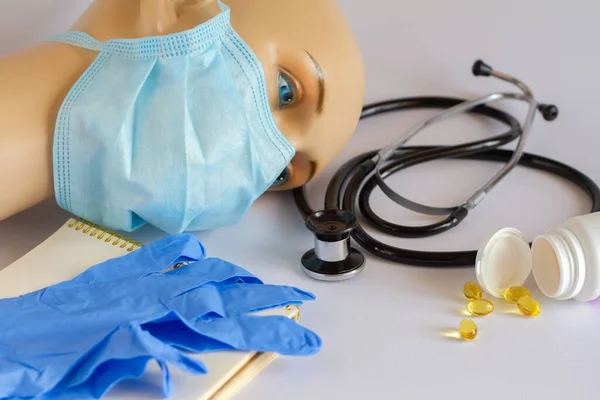 Image with medicine, blue mask on the face of a gypsum mannequin, medical gloves and a stethoscope. vaccine from covid-19