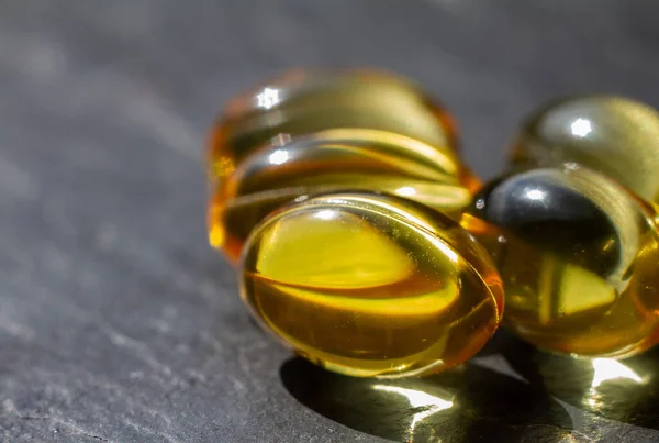 Gel yellow capsules of vitamins and minerals, fish oil, against a dark background