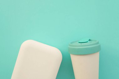 Yeniden kullanılabilir stil çevre dostu bambu bardak ve açık mavi arka planda beslenme çantası..