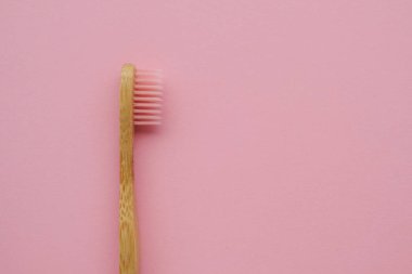 Pembe arka planda ahşap bambu saplı şık çevre dostu doğal diş fırçası..