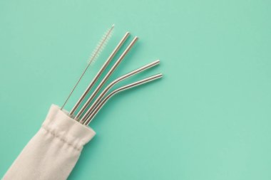 Yeniden kullanılabilir stil çevre dostu sürdürülebilir paslanmaz çelik pipetler açık mavi arka planda.