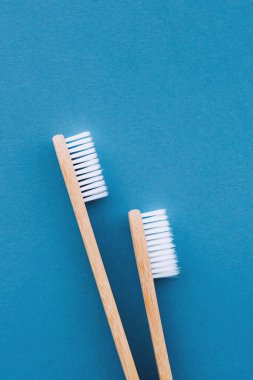 Mavi arka planda ahşap bambu saplı doğal çevre dostu diş fırçaları. Ağız temizliği kavramı. Uzayı kopyala Düz yerde, üst tarafta. Plastik atıkları ve sürdürülebilir yaşam tarzını azaltır.