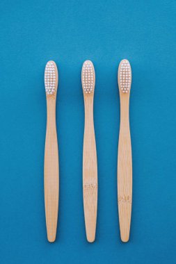 Mavi arka planda ahşap bambu saplı doğal çevre dostu diş fırçaları. Ağız temizliği kavramı. Uzayı kopyala Düz yerde, üst tarafta. Plastik atıkları ve sürdürülebilir yaşam tarzını azaltır.