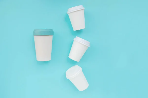 Bring your own cup concept. Reusable eco friendly resistant bamboo cup and many plastic glasses on light blue background. Flat lay. Copy space. Zero waste, no plastic trash.