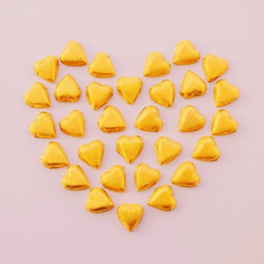 Rgolden sarısından yapılmış kalp şekli pastel arka planda tatlı çikolatalar..