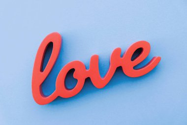 Mavi arka planda kırmızı ahşap kelime aşk, üst manzara.