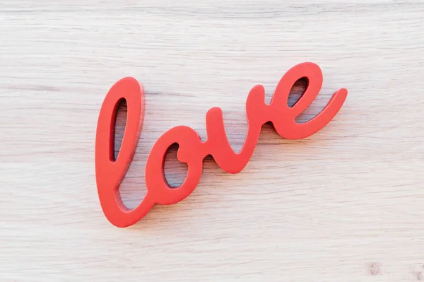 Red letters forming word love on wooden background.
