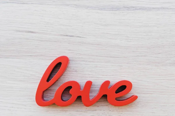 Red letters forming word love on wooden background.