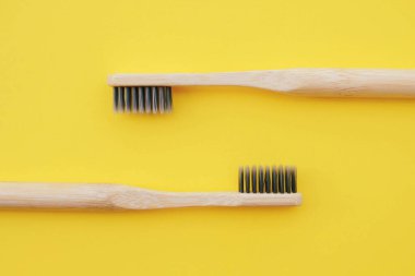 Pastel sarısı arka planda çevre dostu doğal bambu diş fırçaları. Ağız temizliği kavramı. Mesaj için yer var. Düz yatış tarzı, üst görünüm. Plastik atıkları ve sürdürülebilir yaşam tarzını azaltır.