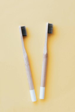 Pastel sarısı arka planda çevre dostu doğal bambu diş fırçaları. Ağız temizliği kavramı. Mesaj için yer var. Düz yatış tarzı, üst görünüm. Plastik atıkları ve sürdürülebilir yaşam tarzını azaltır.