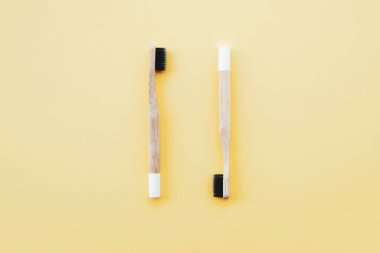 Pastel sarısı arka planda çevre dostu doğal bambu diş fırçaları. Ağız temizliği kavramı. Mesaj için yer var. Düz yatış tarzı, üst görünüm. Plastik atıkları ve sürdürülebilir yaşam tarzını azaltır.