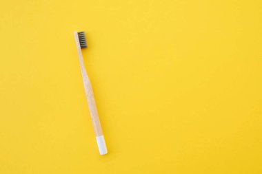 Sarı arka planda çevre dostu doğal bambu diş fırçası. Ağız temizliği kavramı. Uzayı kopyala Düz yatış tarzı, üst görünüm. Plastik atıkları ve sürdürülebilir yaşam tarzını azaltır.