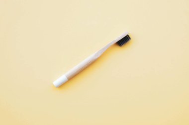 Pastel sarısı arka planda çevre dostu doğal bambu diş fırçası. Ağız temizliği kavramı. Mesaj için yer var. Düz yatış tarzı, üst görünüm. Plastik atıkları ve sürdürülebilir yaşam tarzını azaltır.