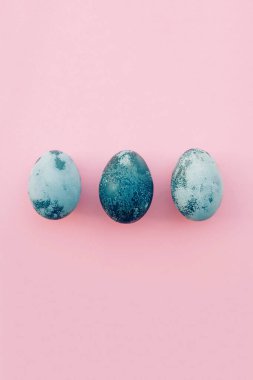 Mutlu Paskalyalar. Doğal boyalı mavi yumurtalar, pastel pembe arka plan, üst manzara. Düz yatıyordu. Metin için maça.
