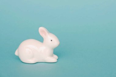 Açık mavi arka planda beyaz Paskalya oyuncak tavşanı, yakın plan. Mesaj için yer var. Mutlu Paskalya tatili kavramı.