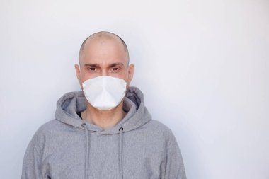 Karantina, hastalık ve ev izolasyonu. Roman Coronavirus, COVID-19 salgını. Beyaz arka planda koruyucu tıbbi maske takan genç bir adam. Metin için boşluk