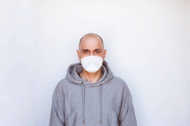 Karantina, hastalık ve ev izolasyonu. Roman Coronavirus, COVID-19 salgını. Beyaz arka planda koruyucu tıbbi maske takan genç bir adam. Metin için boşluk.