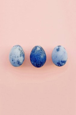 Mutlu Paskalyalar. Doğal boyalı mavi yumurtalar, pastel pembe arka plan, üst manzara. Düz yatıyordu. Metin için maça.