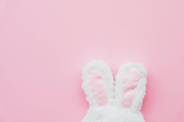 Pastel pembe arka planda komik tavşan kulakları, üst manzara..