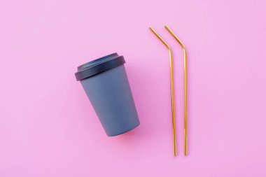 Modern, yeniden kullanılabilen çevre dostu bambu kaplar, pembe arka planda altın pipetler, yüksek açı manzarası. Uzayı kopyala Sıfır atık ve sürdürülebilirlik kavramı.