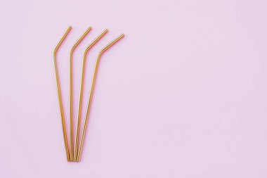Modern, yeniden kullanılabilir, pastel pembe arka planda, çevre dostu altın pipetler, yüksek açı manzarası. Uzayı kopyala, düz yatış stili. Sıfır atık ve sürdürülebilirlik kavramı.