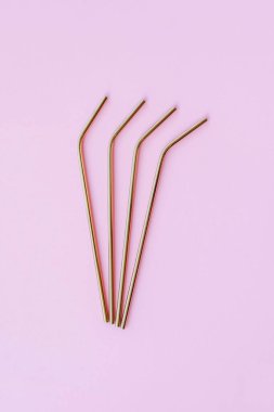 Modern, yeniden kullanılabilir, pastel pembe arka planda, çevre dostu altın pipetler, yüksek açı manzarası. Uzayı kopyala, düz yatış stili. Sıfır atık ve sürdürülebilirlik kavramı.