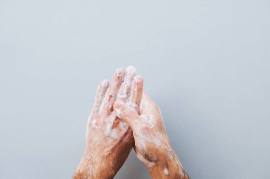 El yıkama konsepti. Adam ellerini açık gri arka plana karşı sıvı dezenfektan sabunla temizliyor. Yaklaş, üst manzara. Uzayı kopyala Düz-Yat. Kişisel hijyen ve Coronavirus önleme.