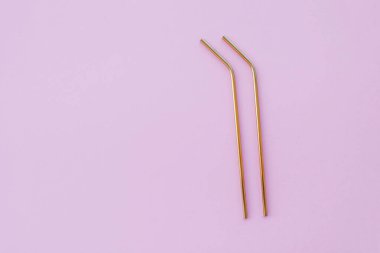 Modern, yeniden kullanılabilir, pastel pembe arka planda, çevre dostu altın pipetler, yüksek açı manzarası. Uzayı kopyala, düz yatış stili. Sıfır atık ve sürdürülebilirlik kavramı.