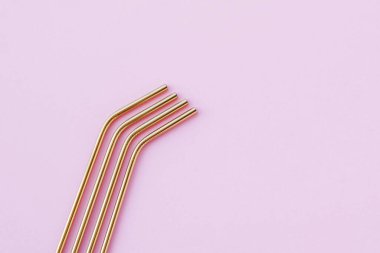 Modern, yeniden kullanılabilir, pastel pembe arka planda, yüksek açılı, çevre dostu altın pipetler. Mesajlaşmak için alan, düz-yatış. Sıfır atık ve sürdürülebilir yaşam tarzı kavramı.