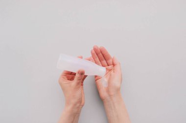Kadın ellerini antiseptik jel kullanarak dezenfekte ediyor, yakın plan, üst görüş. Uzayı kopyala, düz-yatay. Kişisel hijyen, sağlık hizmetleri ve Coronavirus önleme. Antibakteriyel dezenfektan sanitazörü.