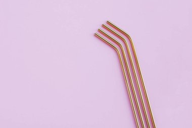 Modern, yeniden kullanılabilir, pastel pembe arka planda, yüksek açılı, çevre dostu altın pipetler. Mesajlaşmak için alan, düz-yatış. Sıfır atık ve sürdürülebilir yaşam tarzı kavramı.