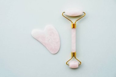 Pembe kuvarstan yapılmış yeşim taşı silindirli, lenfatik drenaj yüz masajı için doğal bir alet. Üst görünüm gri arkaplan, kopyala boşluk, kapat. Güzellik ve vücut bakımı.